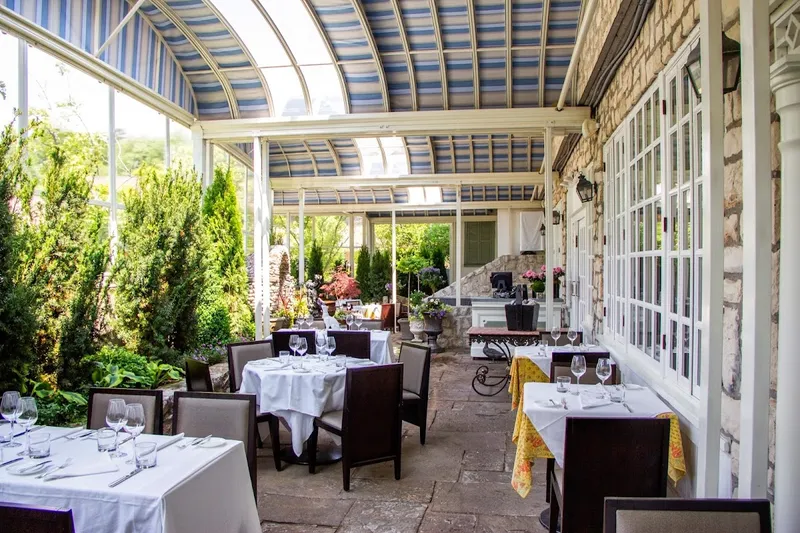 Auberge du Pommier conservatory dining room with white-clothed tables and garden views