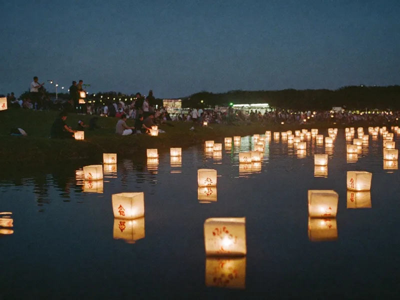 Illustration: paper lanterns glowing on a dark pond at dusk as a crowd releases them from the shore