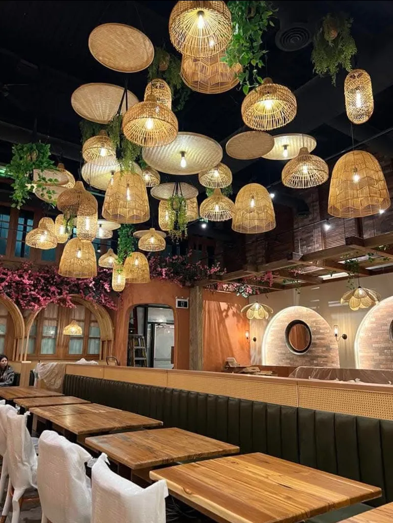 Pho Anh Vu Don Mills branch interior — bamboo pendant lamps, exposed brick arches, and green banquette seating; the chain has three North York locations